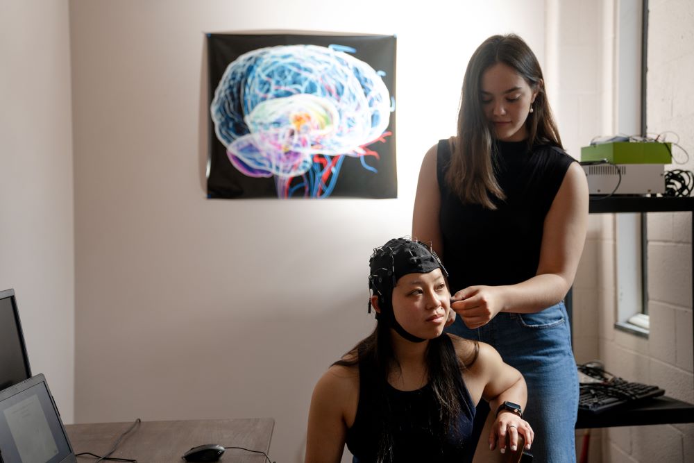 Macey Hoffman '26 (seated) and Erin Dychdala '26 use equipment in Prof.Joel Bish's lab to monitor brain activity.