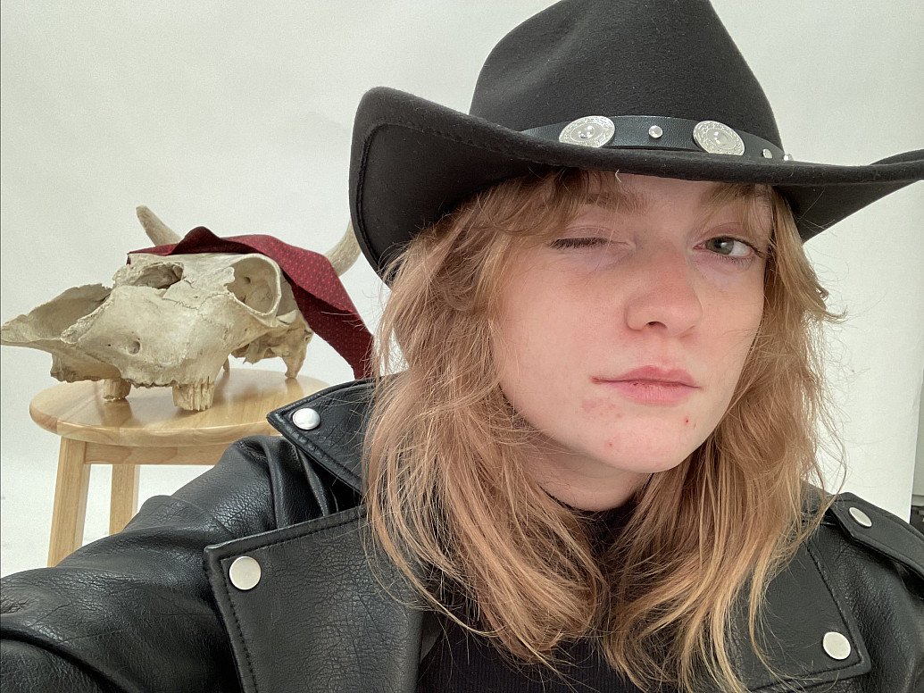 Kelsey in a cowboy hat posing with her art