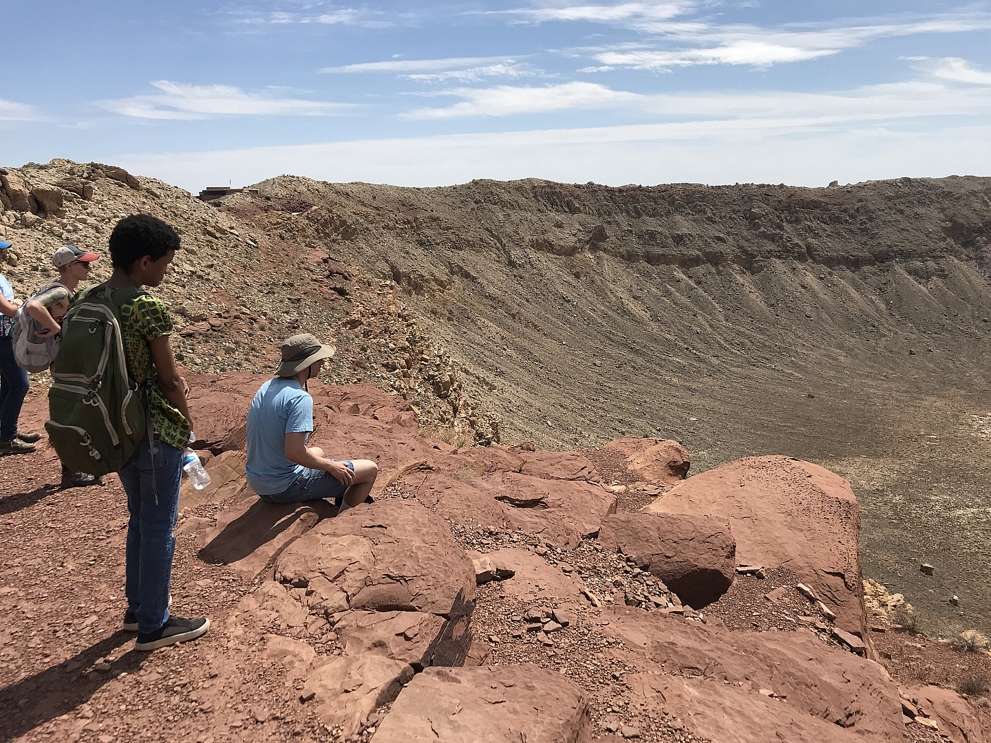 Ursinus students looking down over rim of a meteor crater during a Planetary Crater Consortium (PCC) field trip in August 2019.