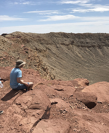 Ursinus students looking down over rim of a meteor crater during a Planetary Crater Consortium (PCC) field trip in August 2019.