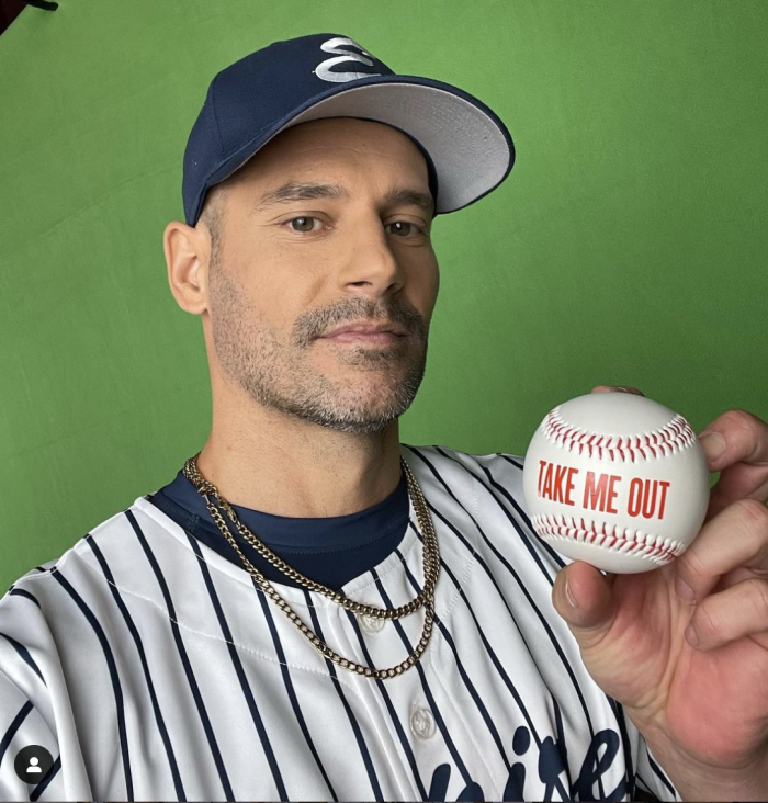 Eduardo Ramos holding up a baseball with inscription, Take Me Out.