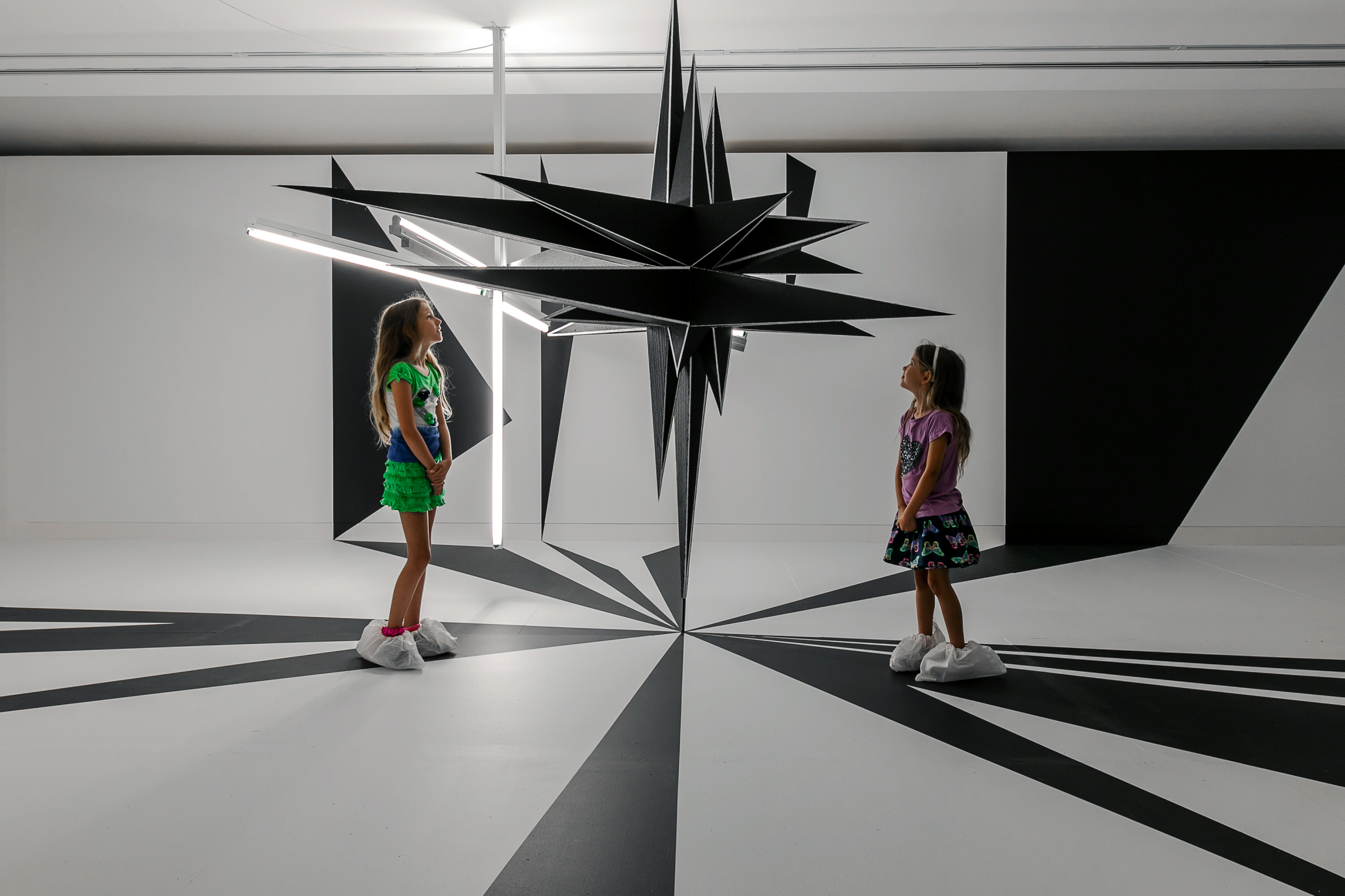 Two children admire a large fixture from Science Fiction, 2019 exhibition.