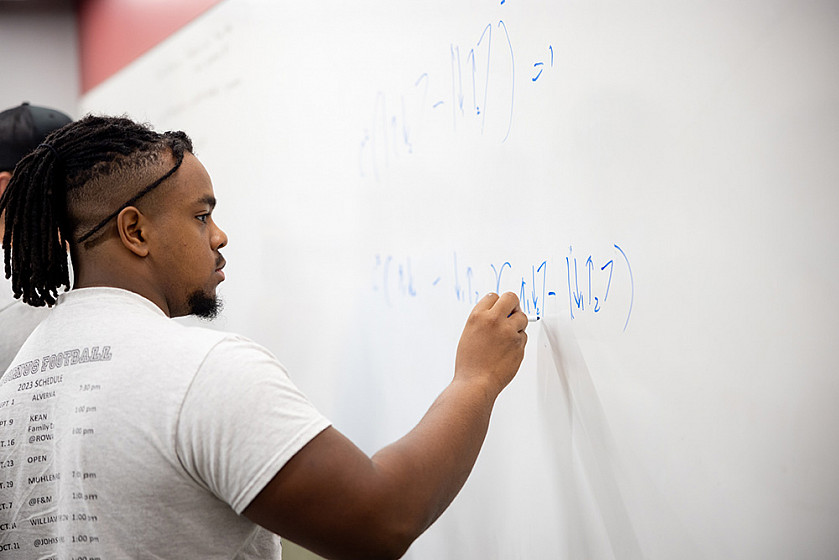 Physics class with student at whiteboard