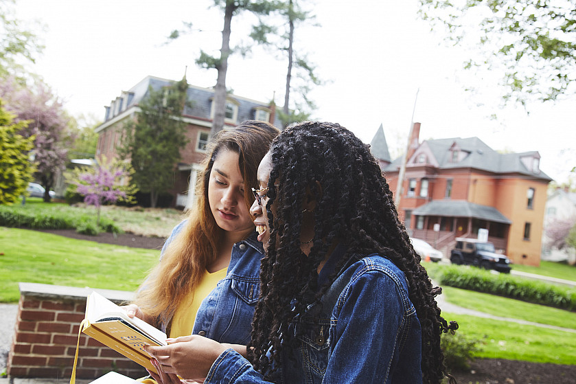 Two roommates talking over their notes outside on campus