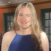 A person with long blonde hair is smiling at the camera